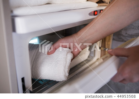 Woman is putting towel in electrical drier Woman is putting towel in electrical drier 44953508