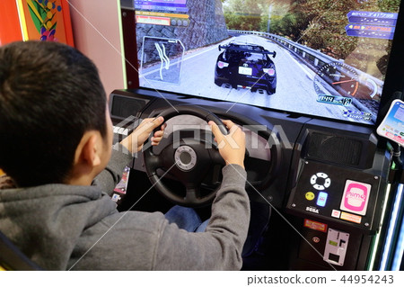 Boy enjoying car racing game in game center Boy enjoying car racing game in game center 44954243