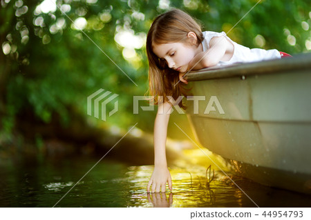 Cute little girl having fun in a boat by a river Cute little girl having fun in a boat by a river 44954793
