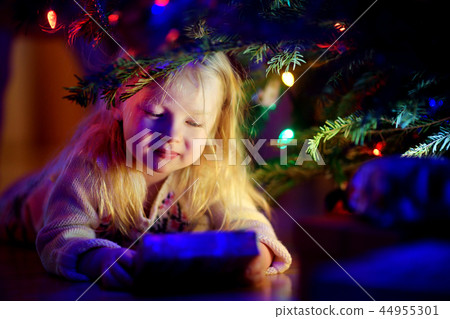 Adorable little girl looking for gifts under a Christmas tree 44955301