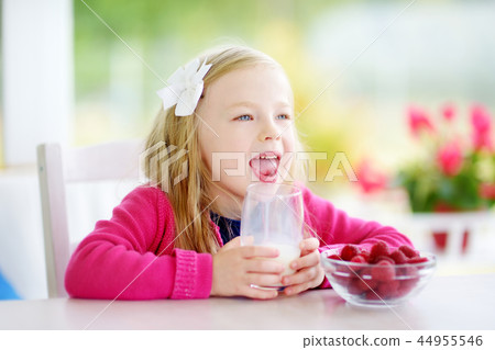 Pretty girl eating raspberries and drinking milk Pretty girl eating raspberries and drinking milk 44955546