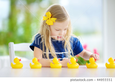 Cute little girl playing with rubber ducklings at home 44955551