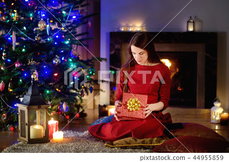 Beautiful woman enjoying her time by a fireplace on Christmas eve 44955859