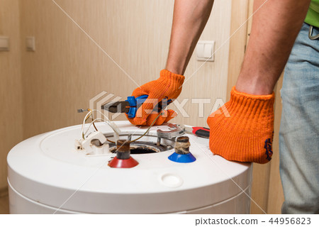 Plumber hands with pliers and screwdriver close up 44956823