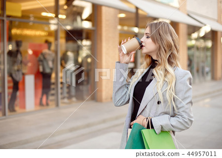 Cute young fashion woman with shopping bags standing near storefront shop windows on the street Cute young fashion woman with shopping bags standing near storefront shop windows on the street 44957011