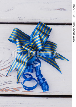 Blue gift bow on white wooden background. Blue gift bow on white wooden background. 44957281