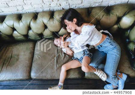 Mom and her little girl have fun on the couch Mom and her little girl have fun on the couch 44957908