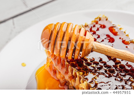 Honeycomb on plate with honey dipper 44957931