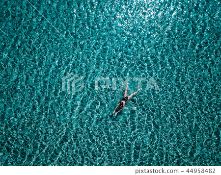 Young girl in a black swimsuit swims in the sea. 44958482
