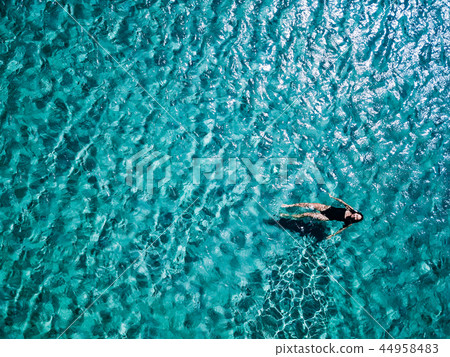 Young girl in a black swimsuit swims in the sea. 44958483