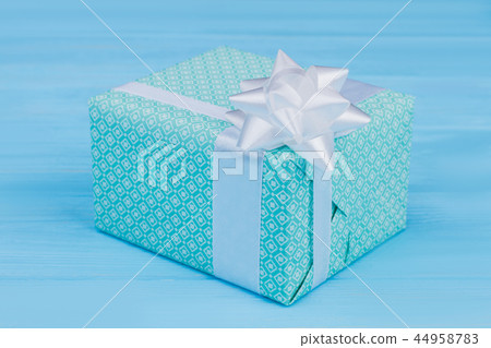 Green patterned gift box with white ribbon. 44958783