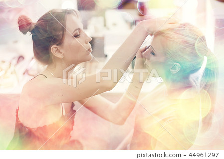 make-up salon on a blurred background with a pink bokeh / client makeup salon, a young girl with beautiful skin and a face doing make-up in the salon 44961297
