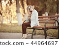 adult girl sitting on a bench in the park / beautiful model woman resting on a bench, cheerful happy girl 44964697