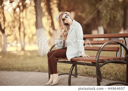 adult girl sitting on a bench in the park / beautiful model woman resting on a bench, cheerful happy girl adult girl sitting on a bench in the park / beautiful model woman resting on a bench, cheerful happy girl 44964697