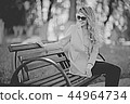adult girl sitting on a bench in the park / beautiful model woman resting on a bench, cheerful happy girl 44964734