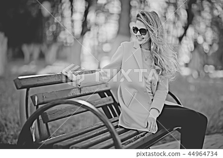 adult girl sitting on a bench in the park / beautiful model woman resting on a bench, cheerful happy girl 44964734