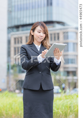 Young woman in suit operating tablet pc 44965473