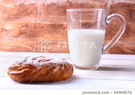 Chocolate and powdered sugar cream puff rings, choux pastry and glass with milk 44968078