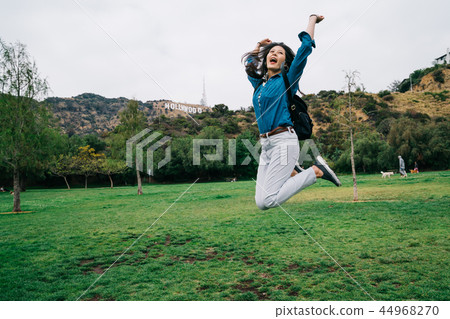 traveler jumping and raising her hands in the sky 44968270