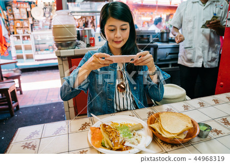 female tourist trying the traditional taco 44968319