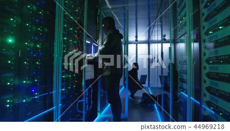 Two hackers in a mask and hoodie on laptops 44969218