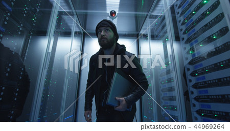 Hacker sneaking through rows of servers with laptop Hacker sneaking through rows of servers with laptop 44969264