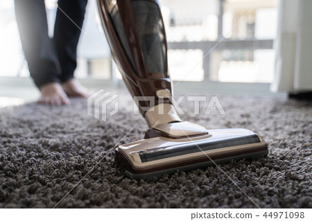 Close-up  man using a vacuum cleaner while  44971098