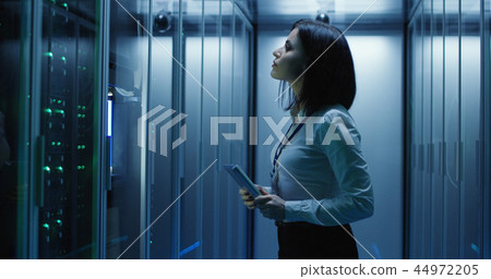 Female technician works on a tablet in a data center 44972205