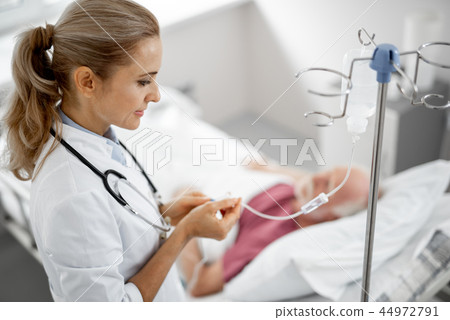 Doctor regulating IV infusion while patient lying in bed 44972791