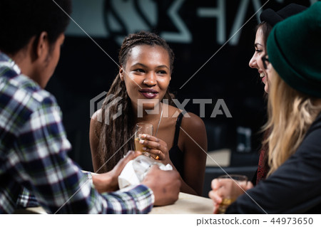 Smiling girl enjoying drinks with her friends Smiling girl enjoying drinks with her friends 44973650