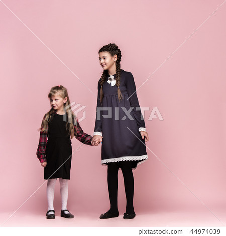 Cute stylish children on pink studio background. The beautiful teen girls standing together 44974039