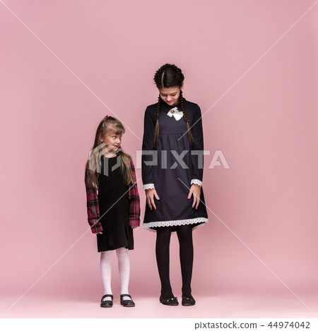 Cute stylish children on pink studio background. The beautiful teen girls standing together 44974042