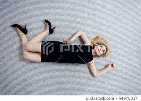 Beautiful dead woman in black dress lying on the floor. 44976017