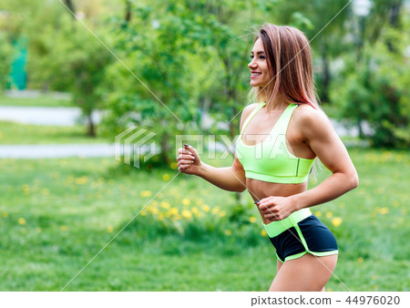 Beautiful young woman running in the green summer park. Beautiful young woman running in the green summer park. 44976020