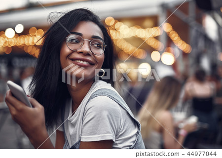Charming girl with cellphone spending time outdoors Charming girl with cellphone spending time outdoors 44977044