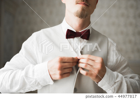 Grooms morning preparation. Handsome man getting dressed and preparing for the wedding Grooms morning preparation. Handsome man getting dressed and preparing for the wedding 44977817