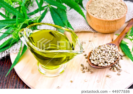 Oil hemp in sauceboat with grain on dark board 44977886