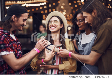 Smiling lady holding little puppy and her friends looking at it 44978224