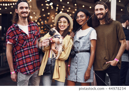 Four friends smiling and posing for photo with cute puppy 44978234