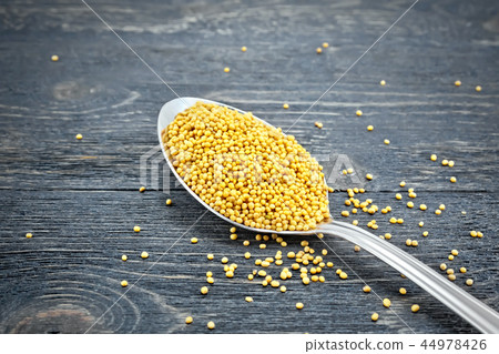 Mustard seeds in metal spoon on black board Mustard seeds in metal spoon on black board 44978426
