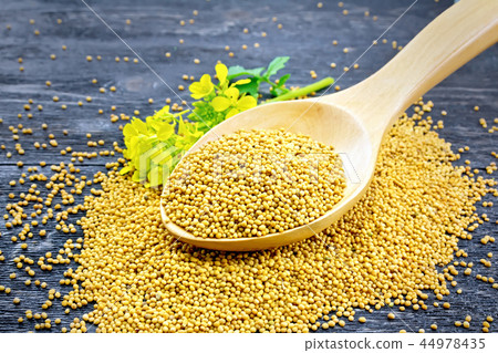 Mustard seeds in wooden spoon with flower on board 44978435
