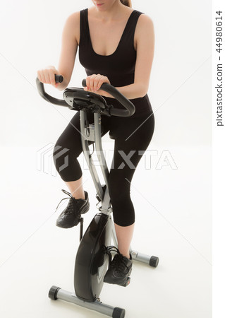 Young woman rowing an exercise bike Young woman rowing an exercise bike 44980614