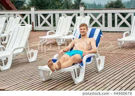 Boy lying on beach chair with towel in blue stripes. Boy lying on beach chair with towel in blue stripes. 44980679