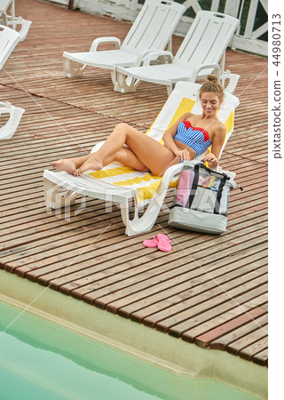 From above view of girl, getting sunblock cream from bag. 44980713