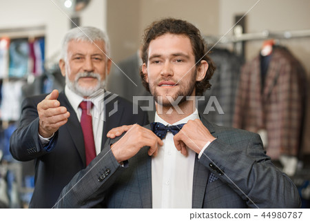 Two happy atractive elegant men choosing clothes for special occaision.  44980787