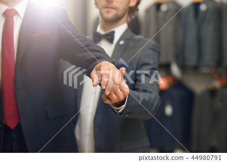 Young salesman with beard helping choosing jacket. 44980791