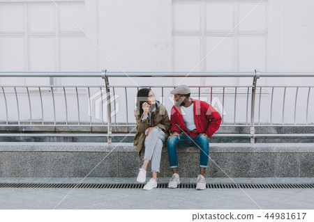 Pleasant international friends sitting in urban settings Pleasant international friends sitting in urban settings 44981617