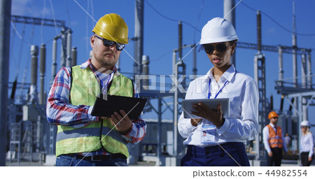 Two electrical workers on tablets outside Two electrical workers on tablets outside 44982554