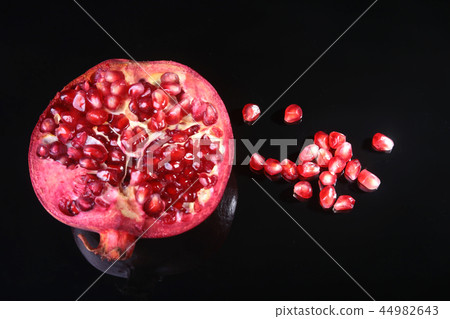 Pomegranate seeds and Beautiful ripe pomegranate on black mirror background with place for copy 44982643