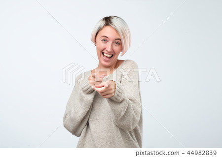 Beautiful young woman points with finger and scoffs, short haircut, studio photo Beautiful young woman points with finger and scoffs, short haircut, studio photo 44982839